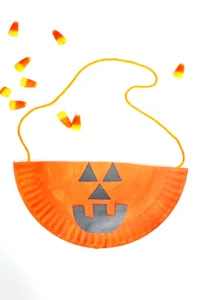 a Paper Plate Jack O Lantern Bag that is a paper plate painted orange with a jack o lantern face