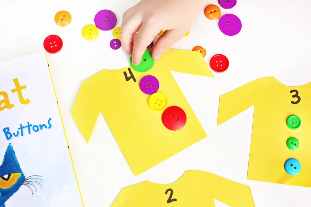 a kid placing buttons on a shirt cut out of yellow construction paper
