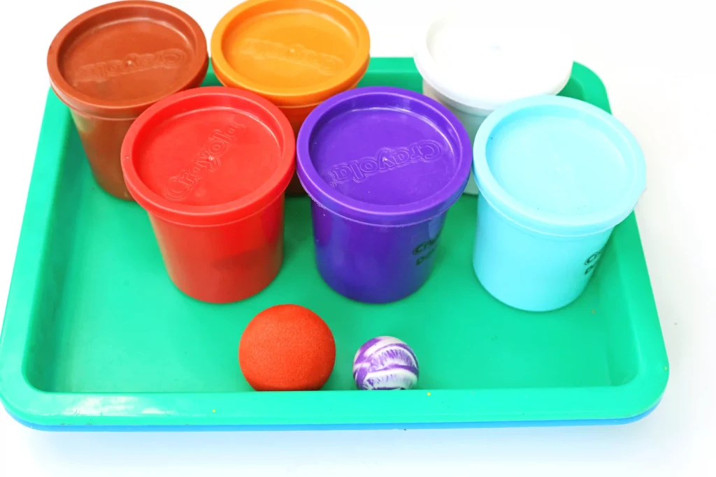 supplies for the STEM playdough pinball activity - playdough in various colors and a marble