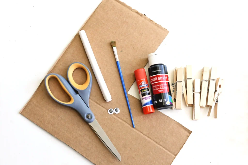 supplies for the spider activity - cardboard, scissors, a white marker, glue, black paint, clothespins, and a paint brush