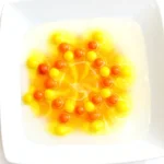 yellow and orange skittles on a plate with water