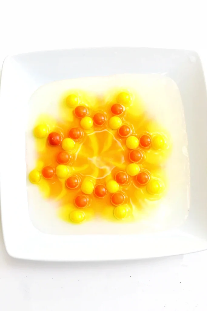 yellow and orange skittles on a plate with water