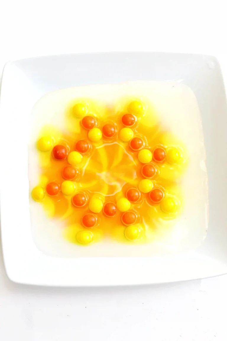 yellow and orange skittles on a plate with water