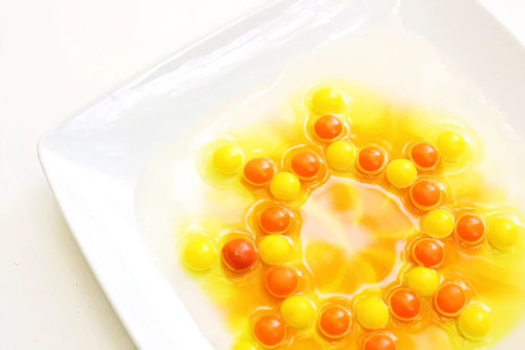red and orange skittles on a plate with water
