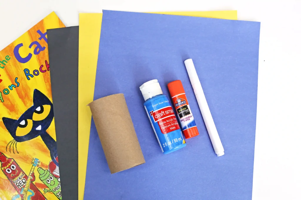 supplies for the toilet paper pete the cat: black, yellow, and blue construction paper, a toilet paper roll, blue paint, a glue stick, and a white marker