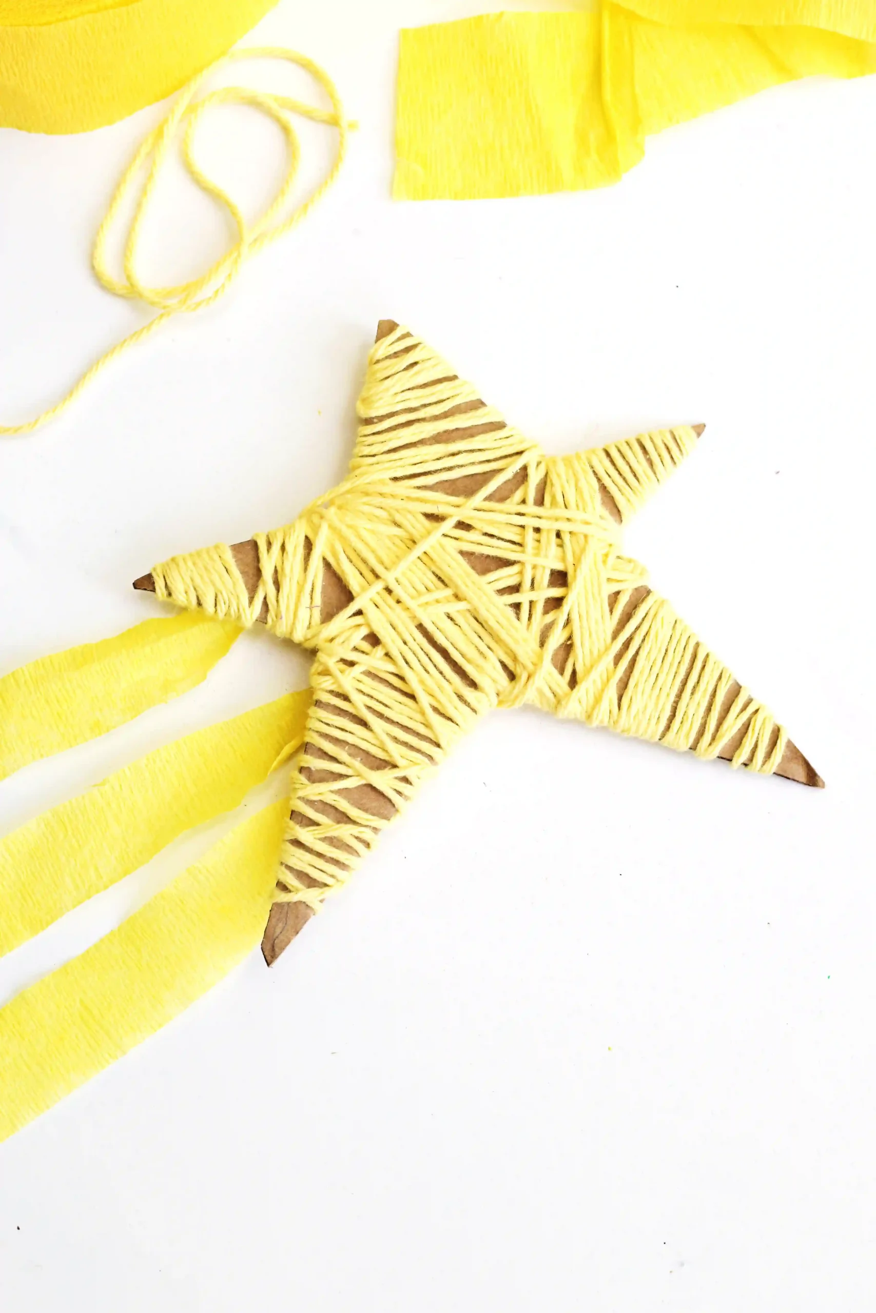 a Yarn-Wrapped Shooting Star Craft that is cardboard cut into a star and wrapped with yellow yarn and has yellow streamers attached