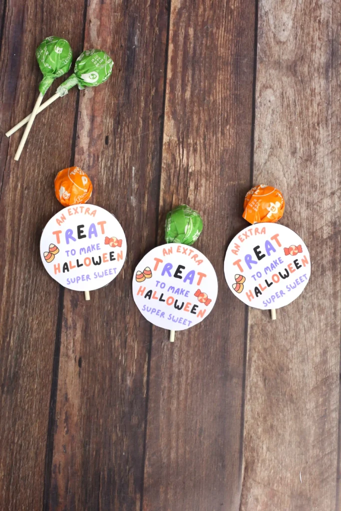 Printable Halloween tags that say "an extra treat to make Halloween sweet" attached to a lollipop
