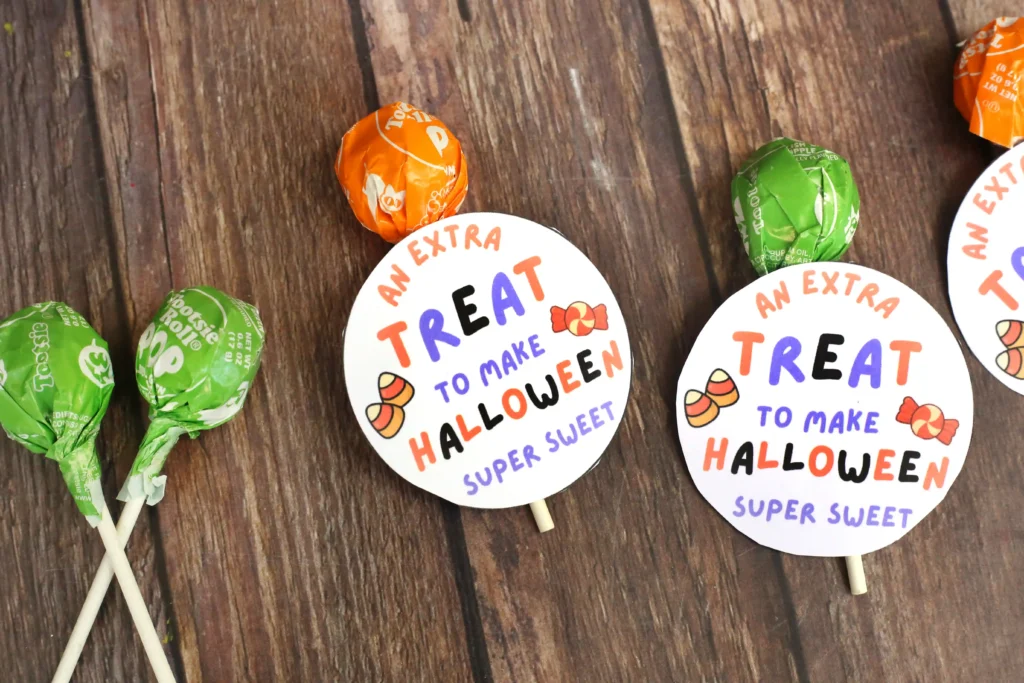 Printable Halloween tags that say "an extra treat to make Halloween sweet" attached to a lollipop
