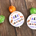 Printable Halloween tags that say "an extra treat to make Halloween sweet" attached to a lollipop