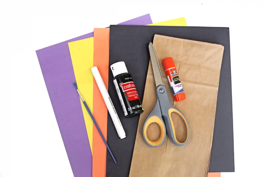 supplies for the black cat paper bag craft- colored construction paper, a paper bag, black paint, scissors, and glue