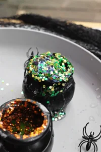 cauldrons with baking soda, vinegar, food coloring, and glitter to make halloween volcanoes