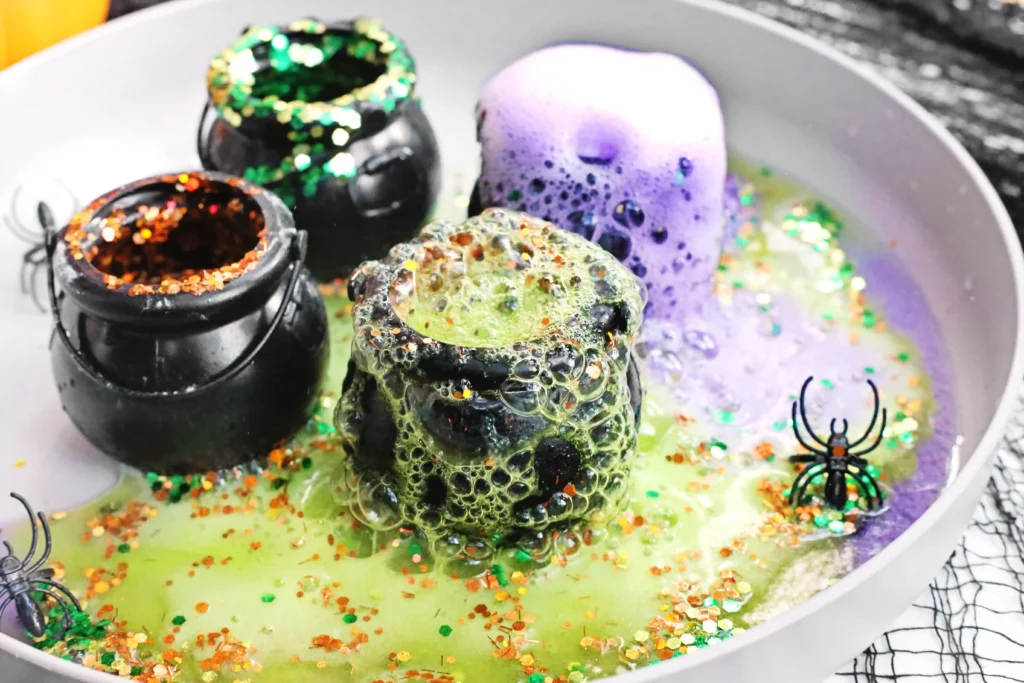 cauldrons with baking soda, vinegar, food coloring, and glitter to make halloween volcanoes