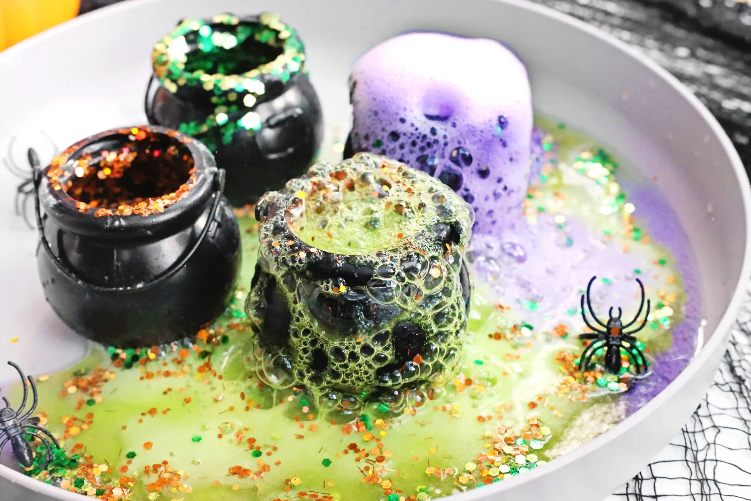 cauldrons with baking soda, vinegar, food coloring, and glitter to make halloween volcanoes