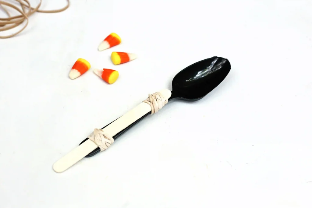 a spoon with popsicle sticks attached using rubber bands