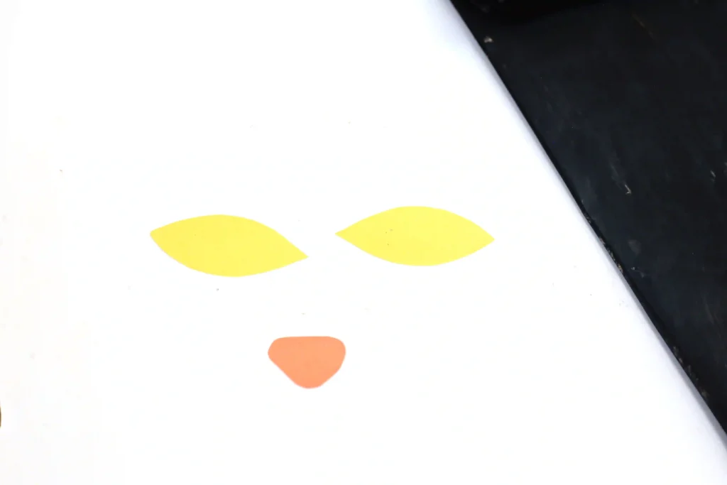 eyes and a nose cut out of yellow and orange construction paper