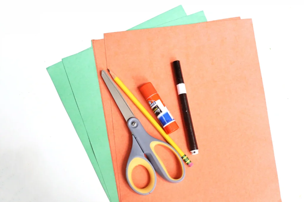 supplies for the DIY Halloween countdown: orange and green construction paper, scissors, glue, a pencil, and a black marker