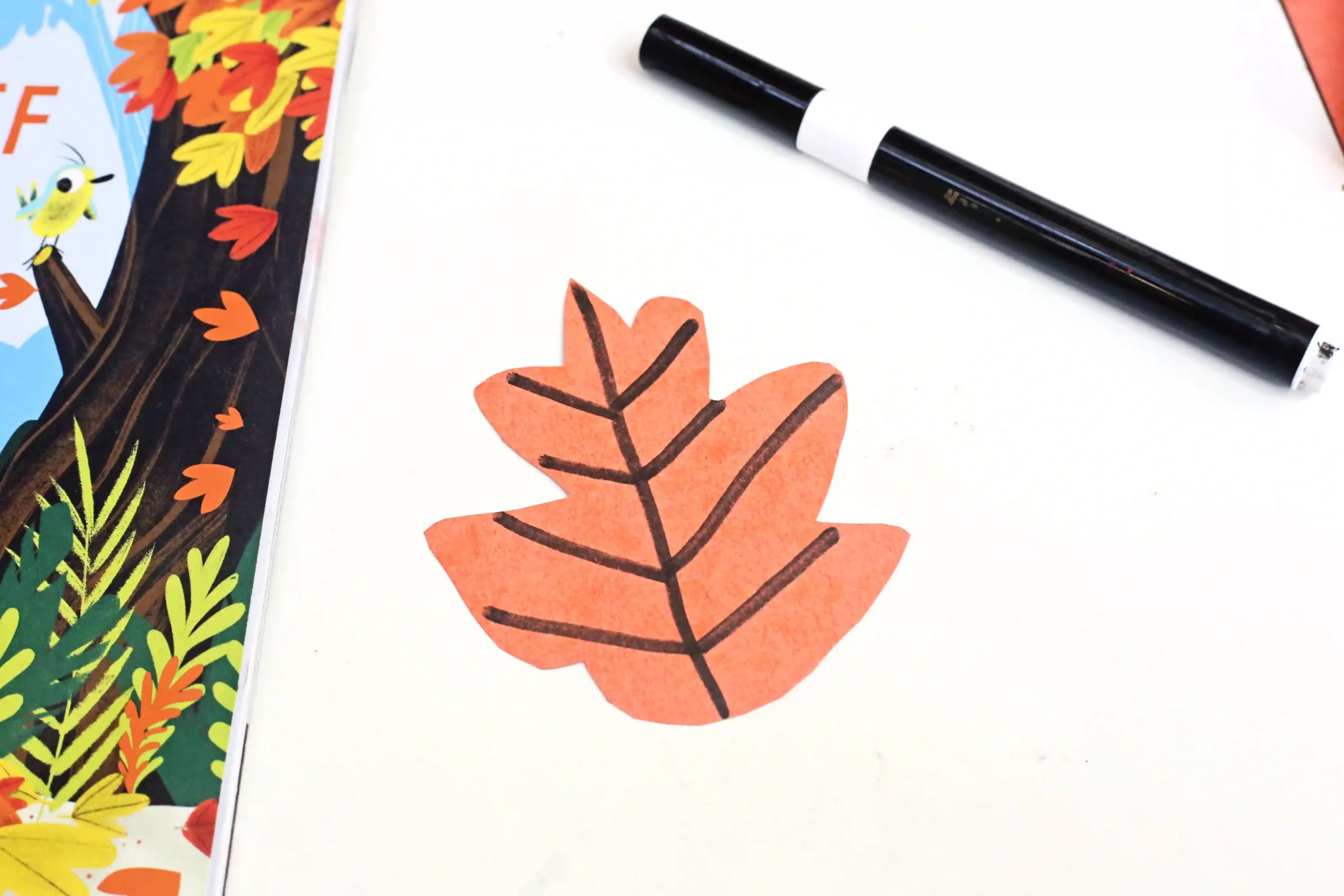 an orange construction paper leaf with veins drawn on in black marker