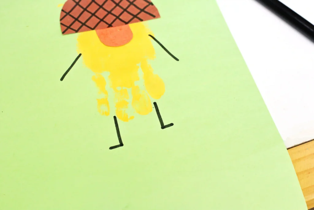 a handprint craft that is a yellow acorn with an orange nose