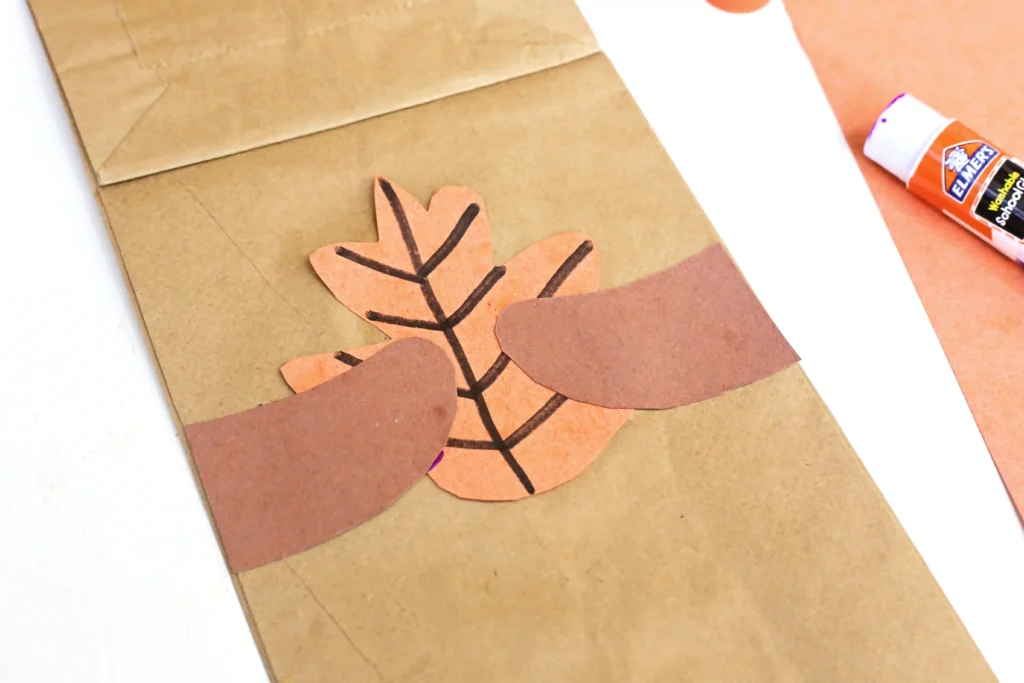 a paper bag with squirrel arms holding a leaf glued on