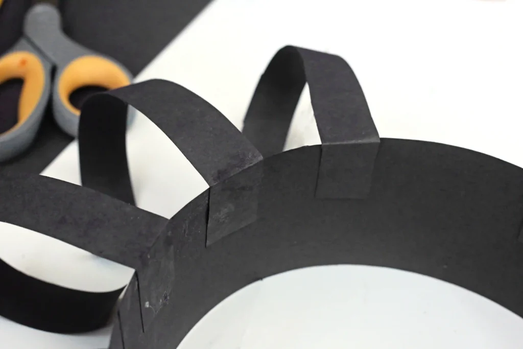 a black construction paper headband with smaller strips of construction paper glued on