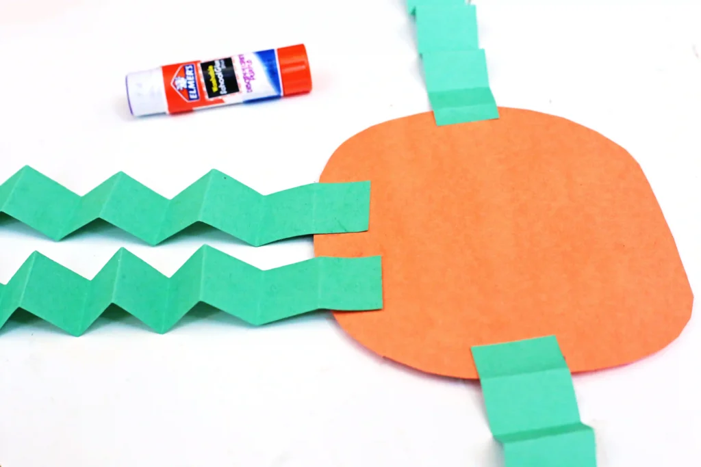 an orange circle with green folded strip glued to it