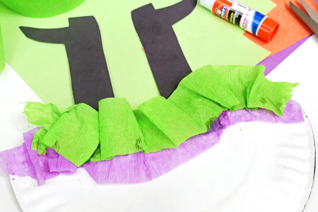 a paper plate with witch legs and streamers