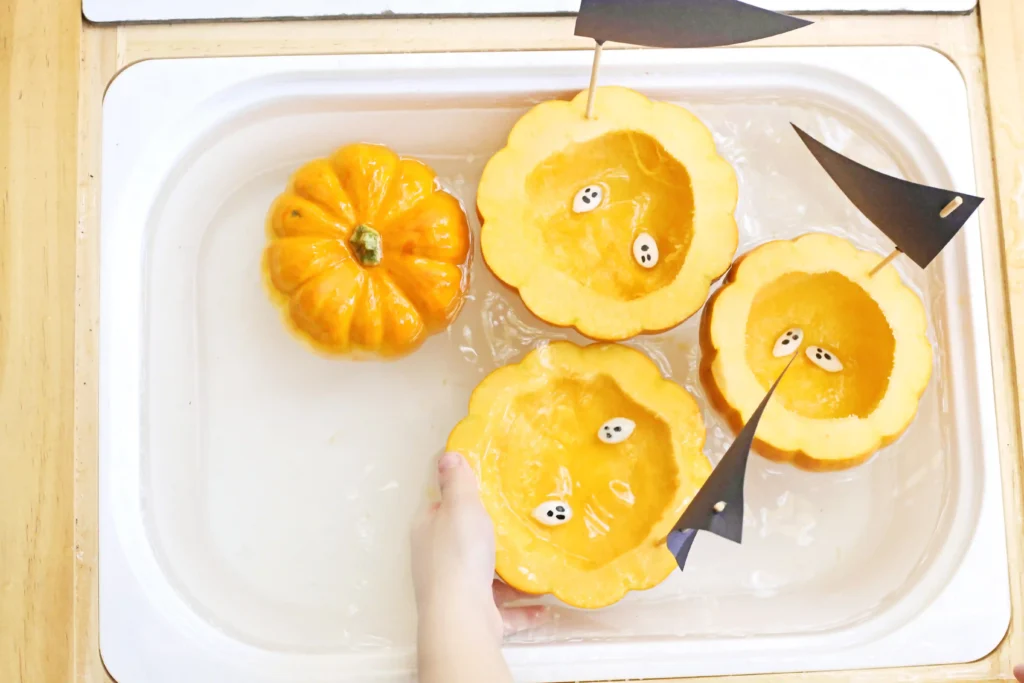 a kid putting pumpkin seeds in a hollowed out pumpkin in water