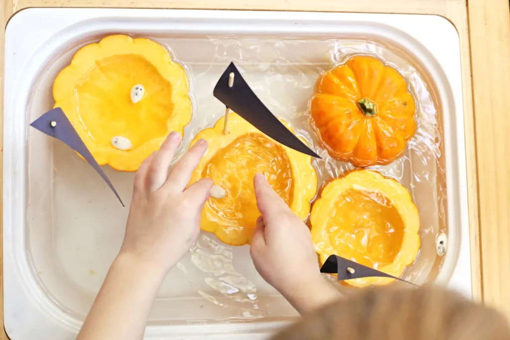 a kid putting pumpkin seeds in a hollowed out pumpkin in water