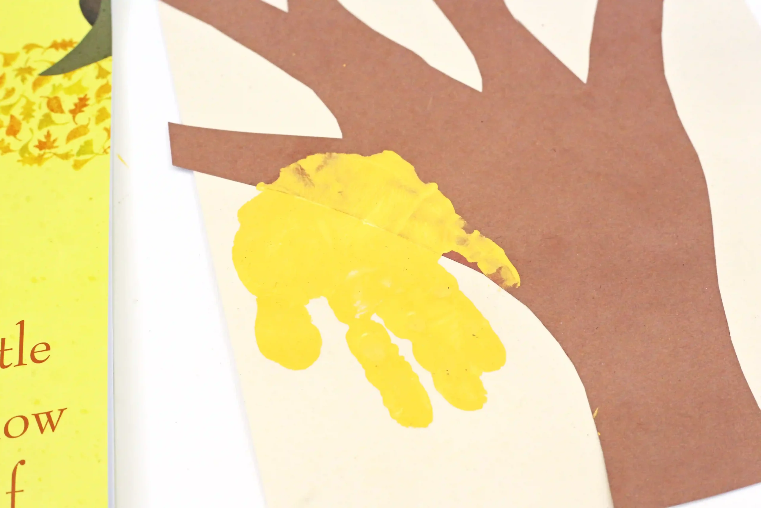 a brown construction paper tree with a yellow handprint on it