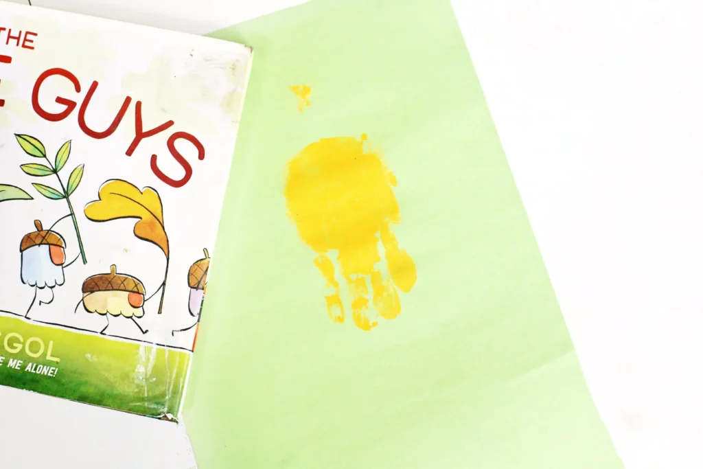 a green piece of construction paper with a yellow handprint on it