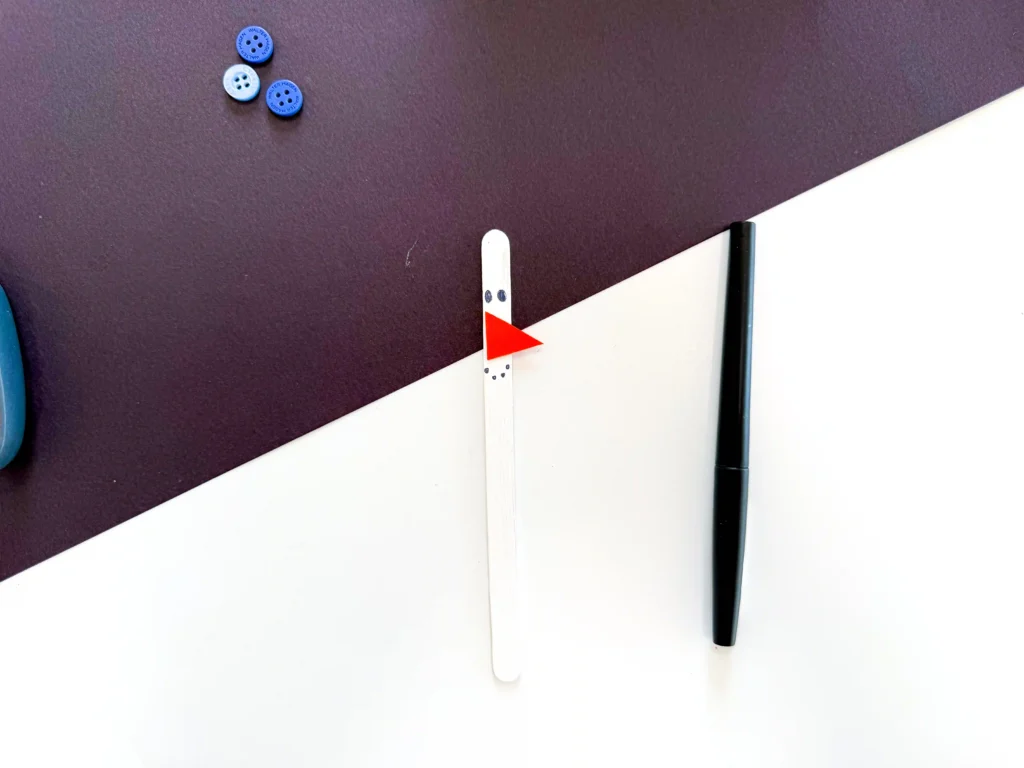 a popsicle stick painted white with an orange nose and a face drawn on