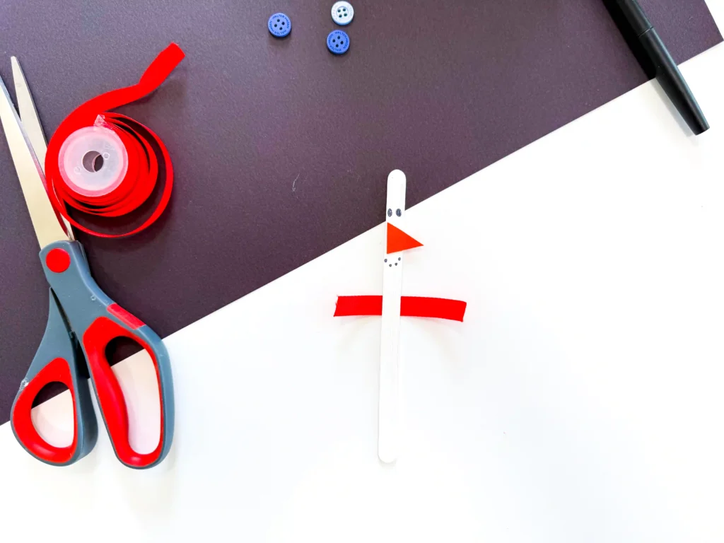 a popsicle stick painted white with a snowman face and a ribbon glued to the back