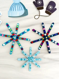 popsicle sticks painted blue and glued together to look like snowflakes with gems on them
