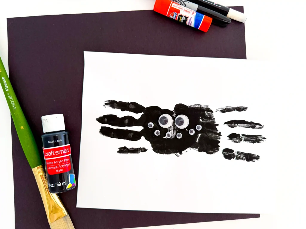 two black handprints with googly eyes to look like a spider