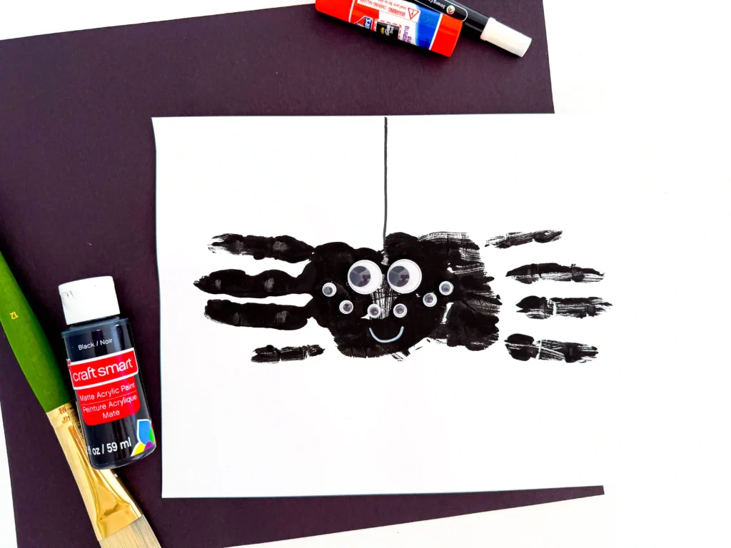 two black handprints with googly eyes to look like a spider