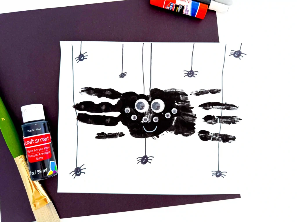 two black handprints with googly eyes to look like a spider