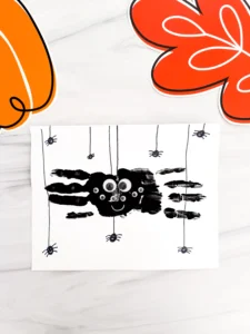a Spider Handprint Craft on a piece of paper on a marbled surface