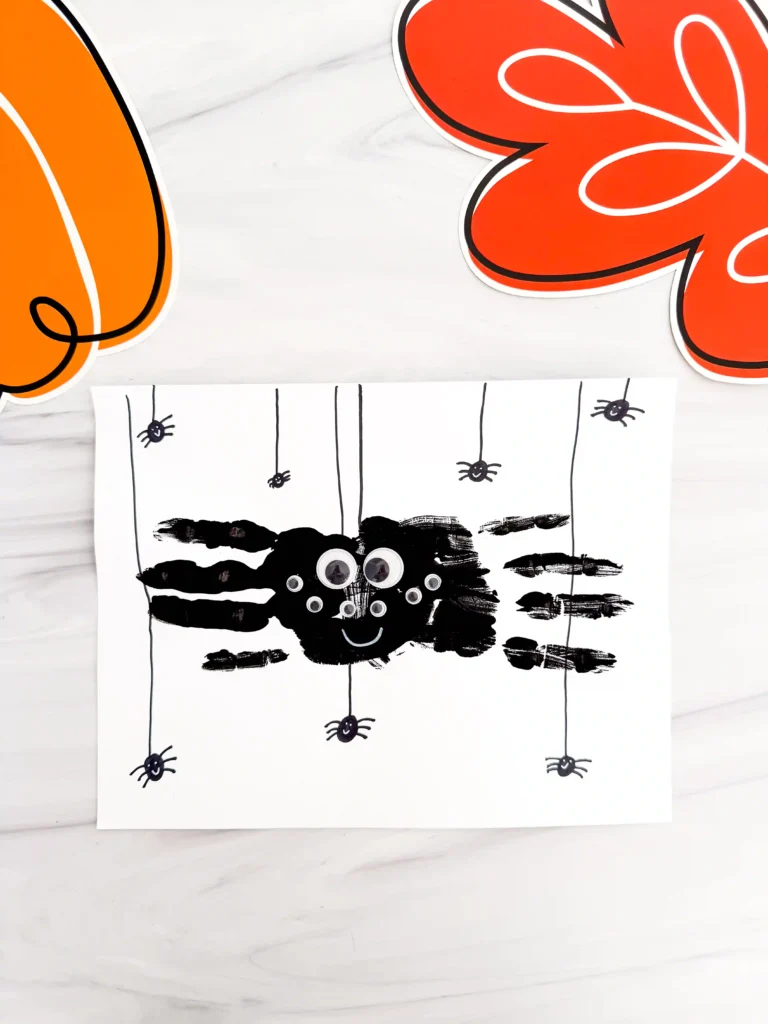 a Spider Handprint Craft on a piece of paper on a marbled surface
