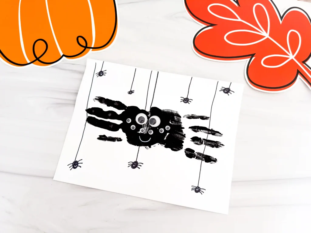 a Spider Handprint Craft on a piece of paper on a marbled surface