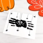 a Spider Handprint Craft on a piece of paper on a marbled surface