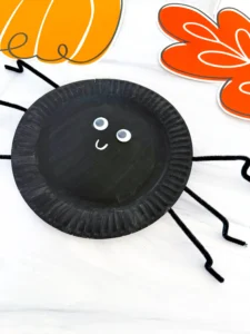 a paper plate painted black and decorated to look like a spider