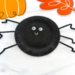 a paper plate painted black and decorated to look like a spider