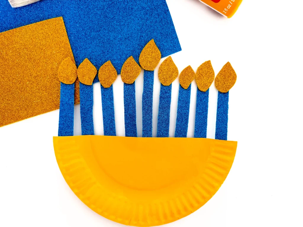 a paper plate painted yellow with glittery candles to look like a menorah