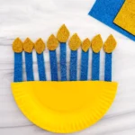 a paper plate painted yellow with glittery candles to look like a menorah