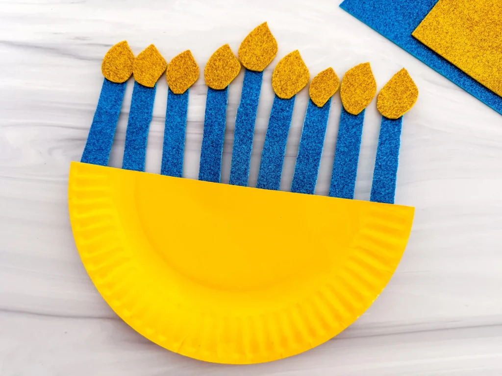 a paper plate painted yellow with glittery candles to look like a menorah