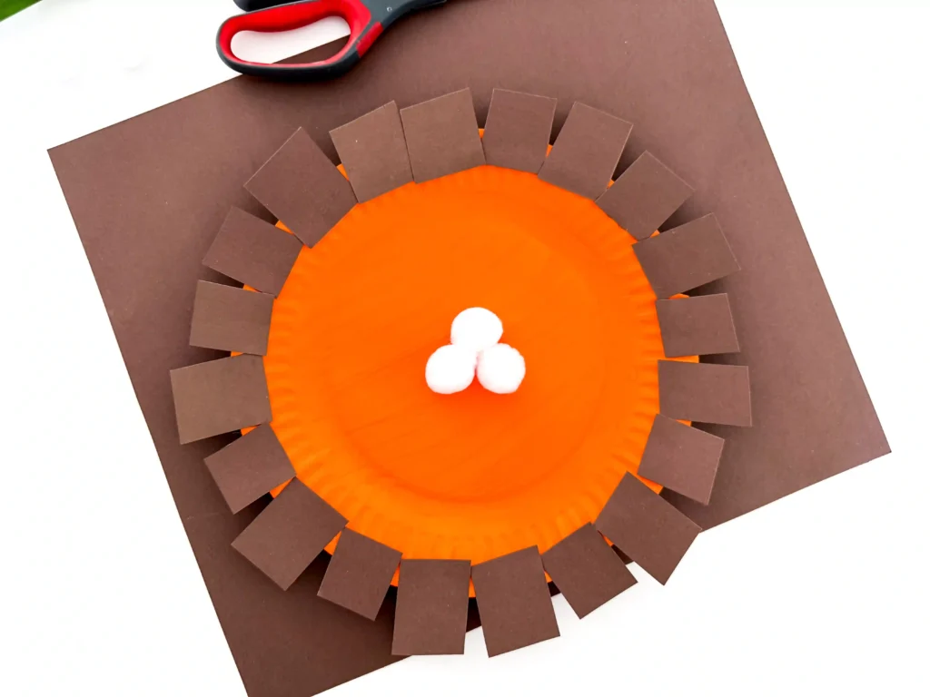 a paper plate painted orange and decorated to look like pumpkin pie