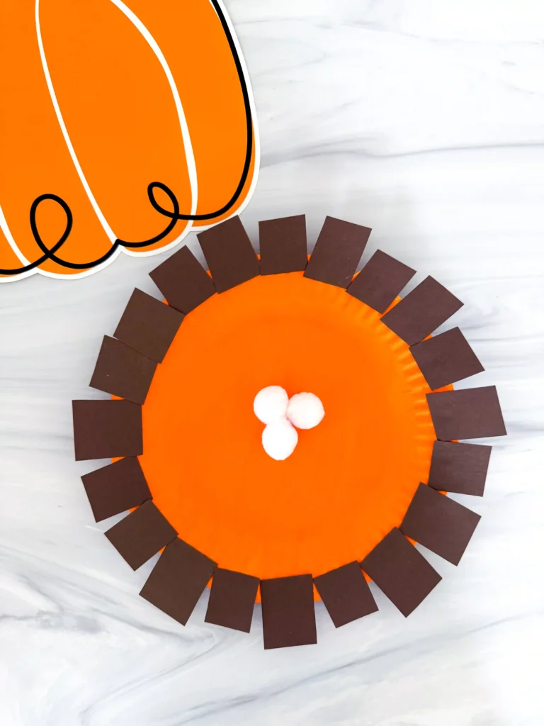 a paper plate painted orange and decorated to look like pumpkin pie