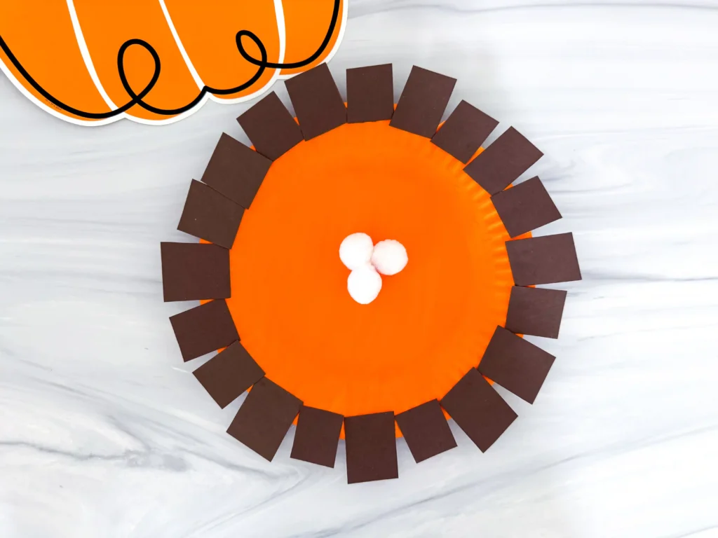 a paper plate painted orange and decorated to look like pumpkin pie
