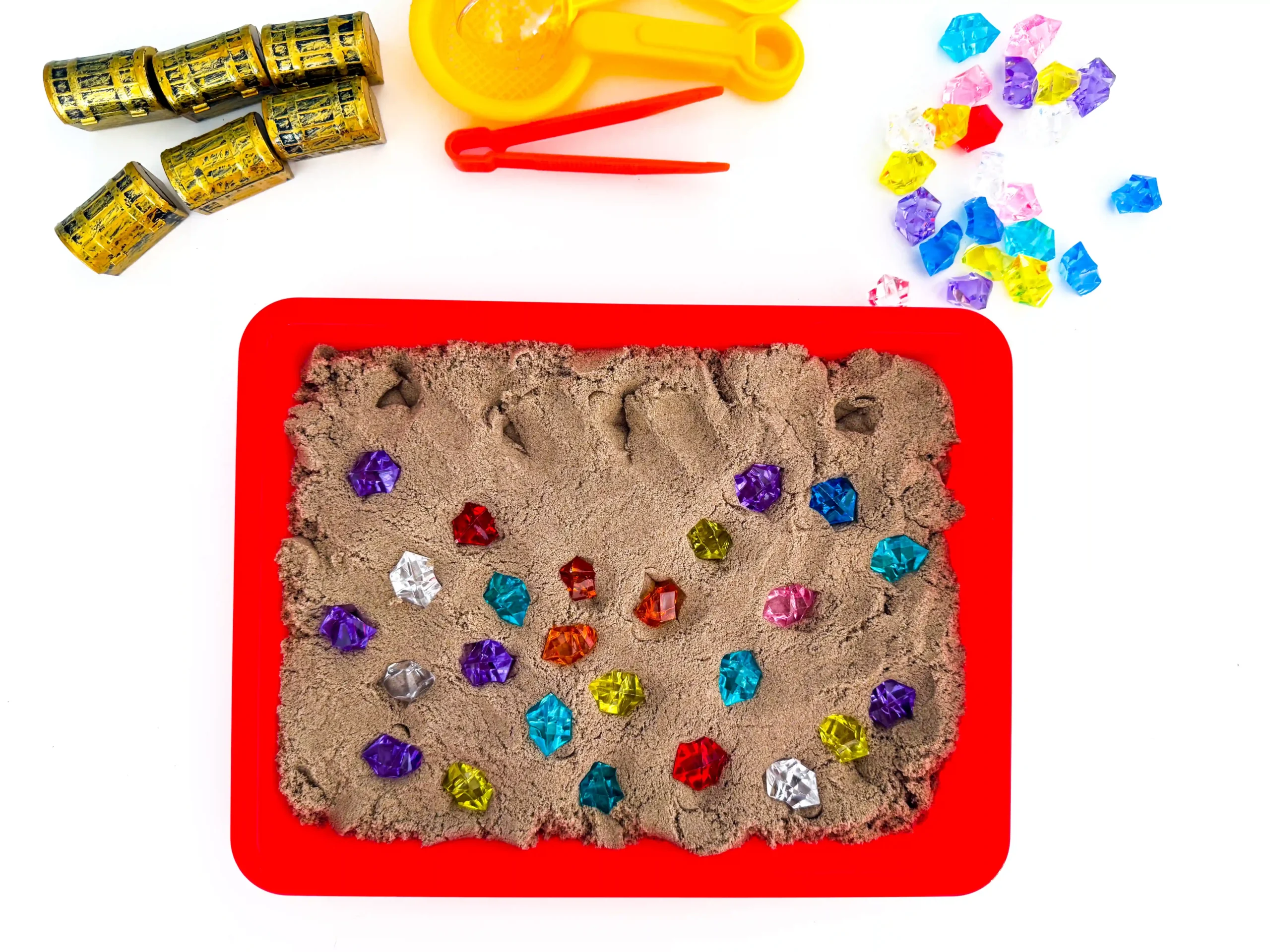 a red tray with kinetic sand and gems