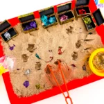 a Treasure Hunt Sensory Bin with kinetic sand, and gems in treasure chests
